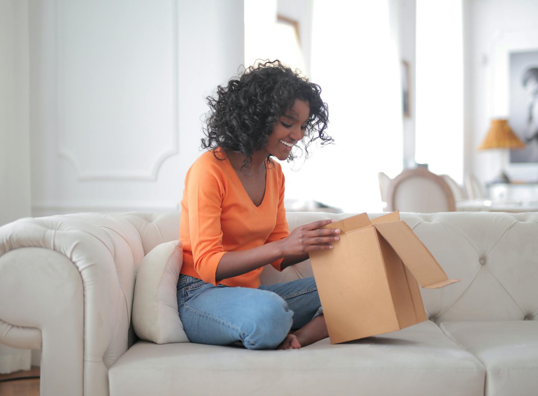 Cheerful African American woman unpacking parcel