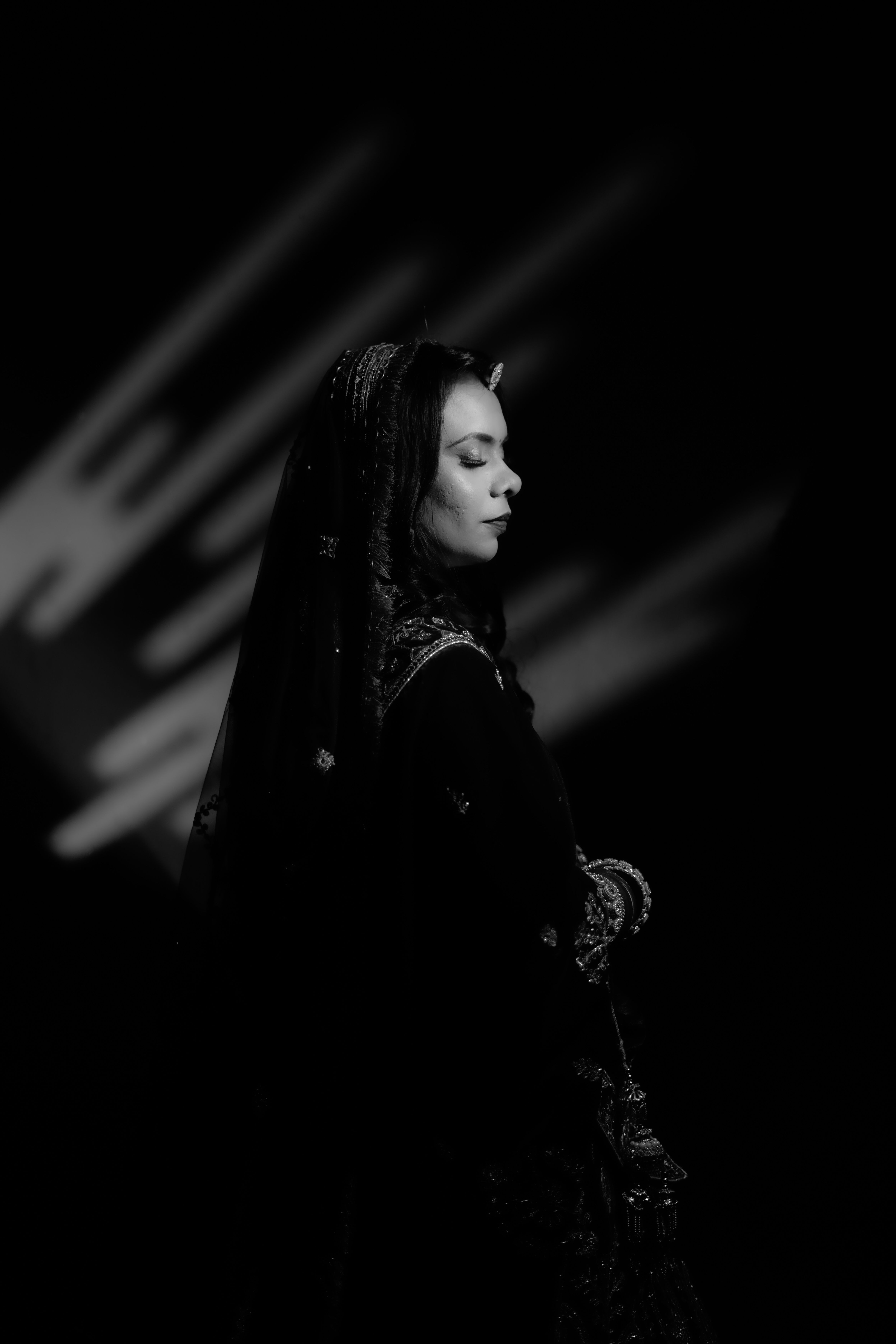 Black and white portrait of a woman in traditional attire, captured in artistic lighting.