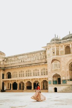 A woman in a colorful dress twirls at the historic Amber Fort in Jaipur, India.