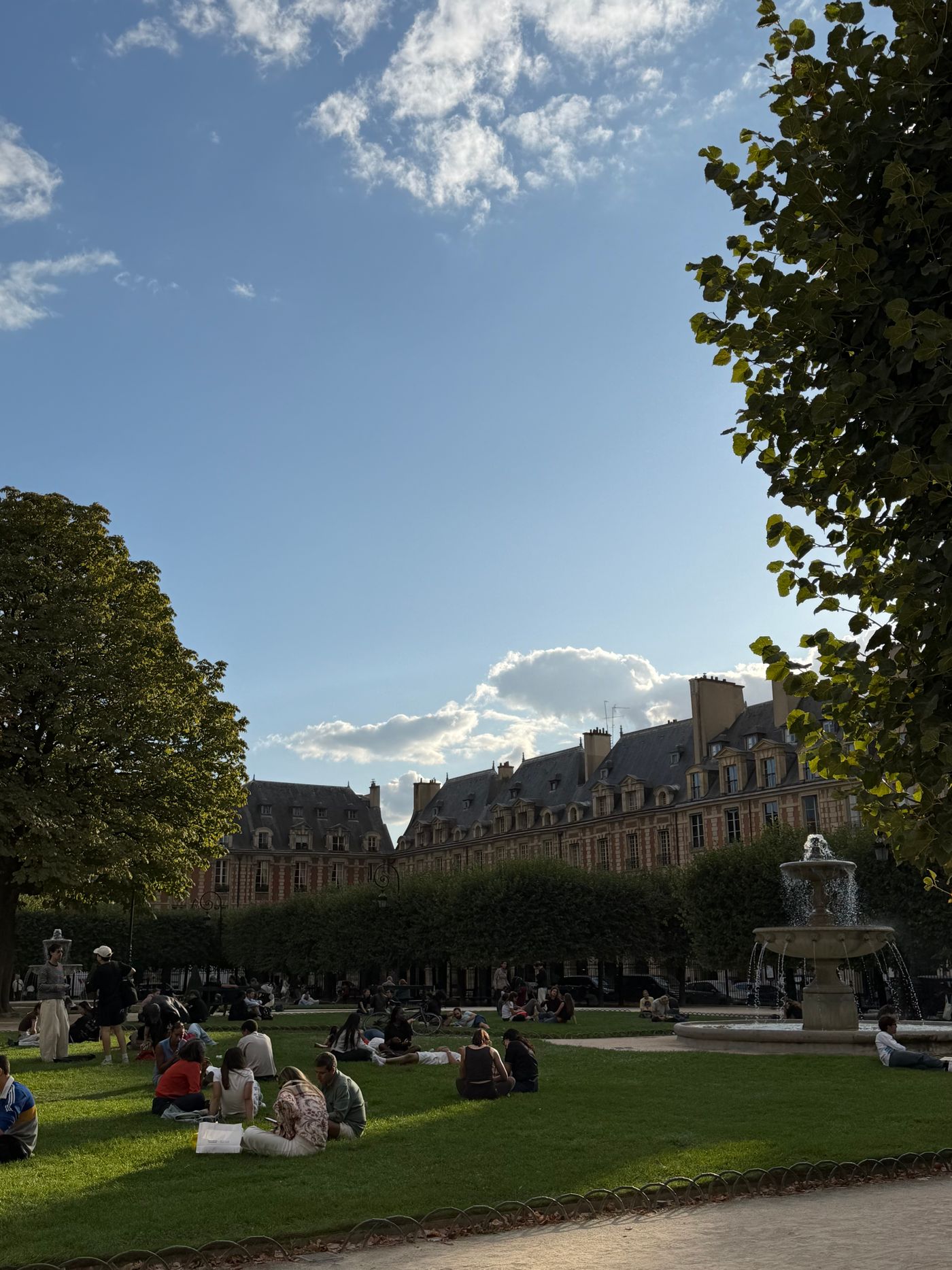 Promeneurs sur la place des Vosges, à Paris, un après-midi ensoleillé