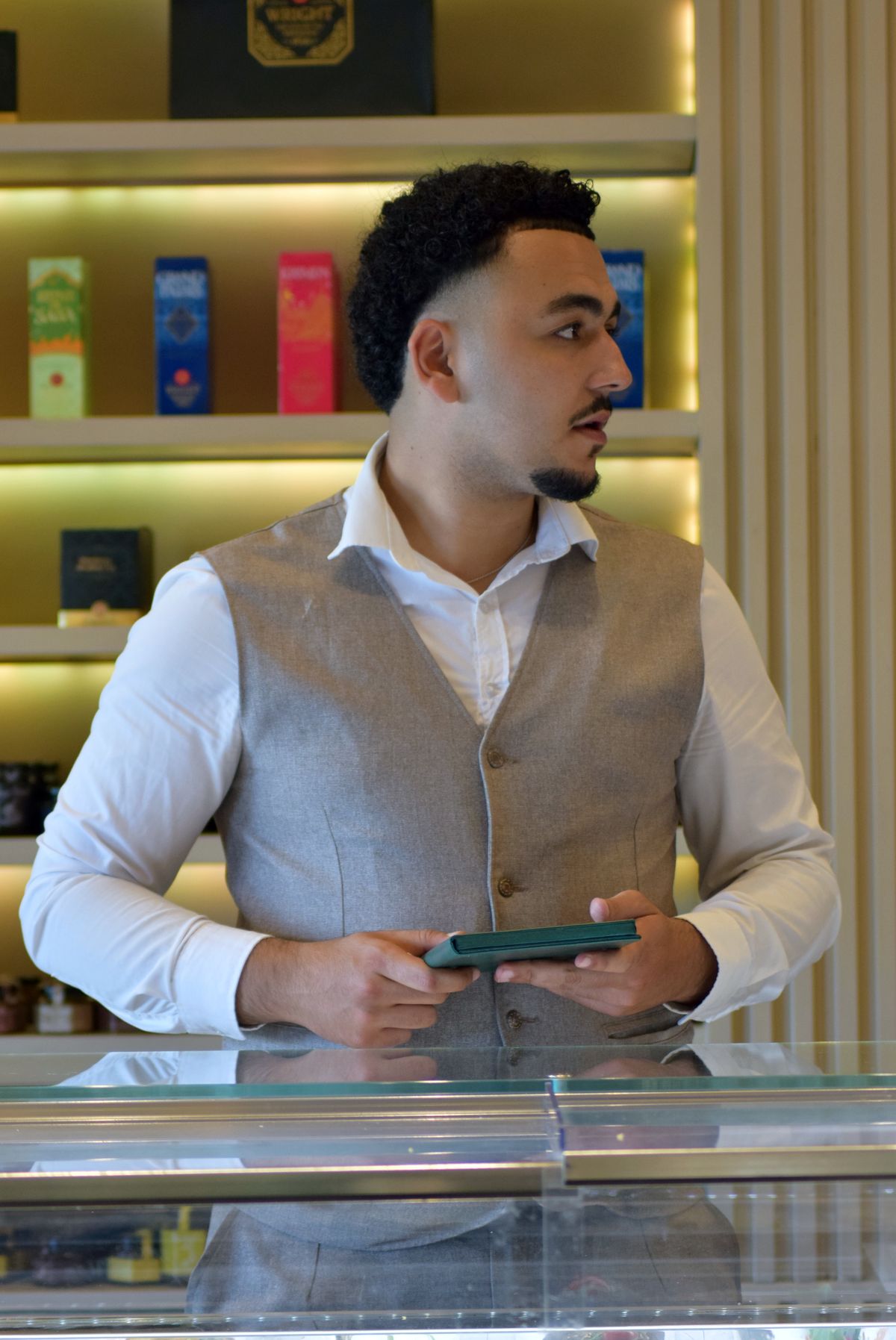 A retail buyer holding a tablet in front of a lit product shelf