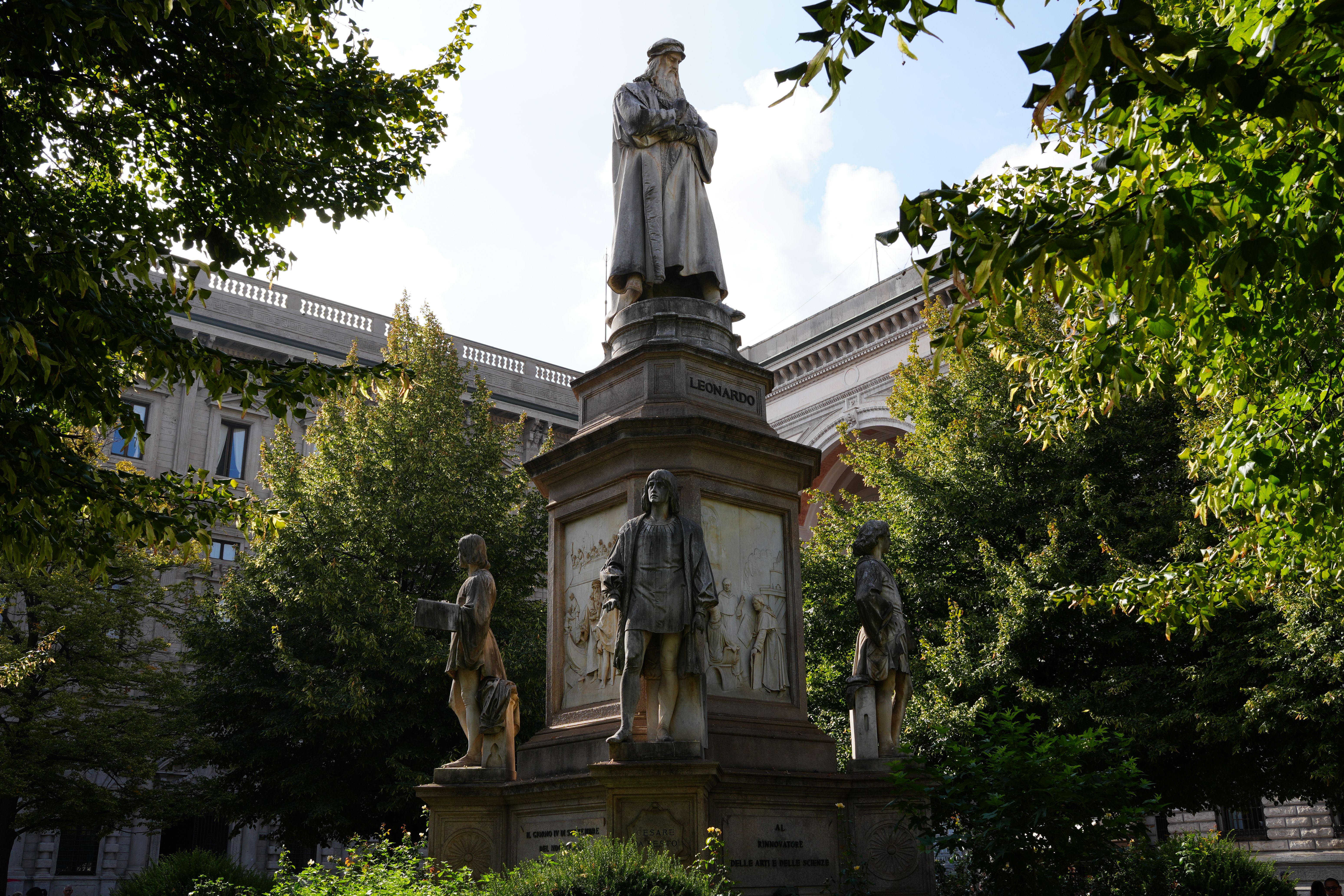 Statue of Leonardo da Vinci surrounded by lush greenery in Milan, Italy.