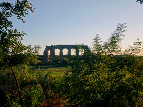 Free Sunset view of ancient Roman aqueduct amidst lush green landscape, creating a serene and historic scene. Stock Photo