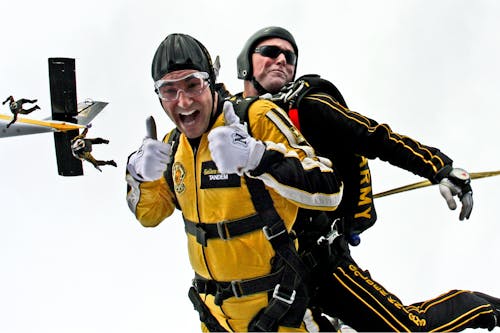 gratis Parachuter In Geel Pak Doet Een Duim Omhoog Stockfoto
