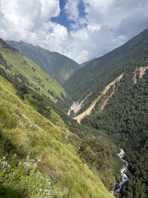 Free Stunning landscape of a lush, green Himalayan valley with flowing river and cloudy skies. Stock Photo