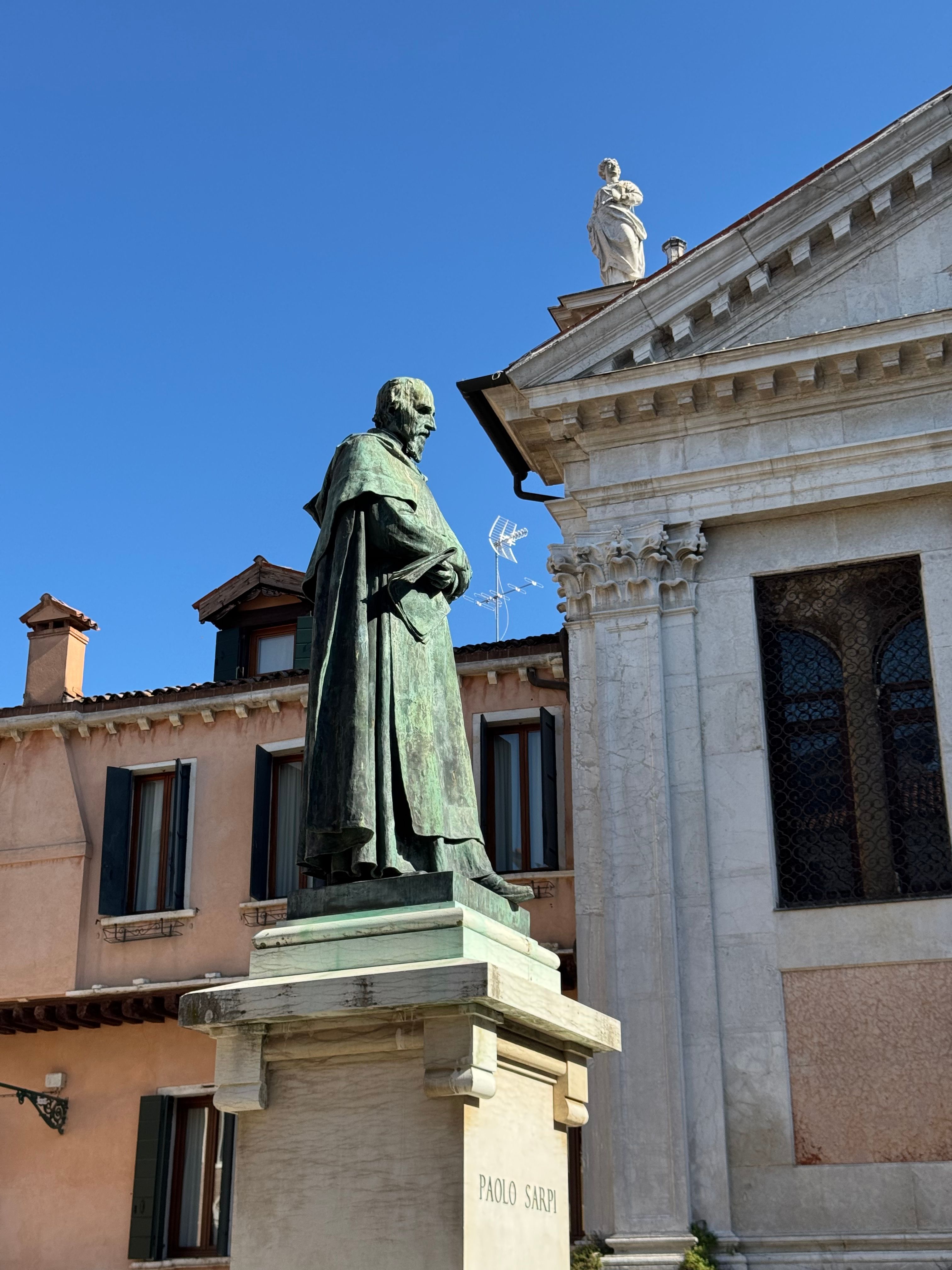 Bronze statue of Paolo Sarpi in Venice, Italy, under a clear blue sky.