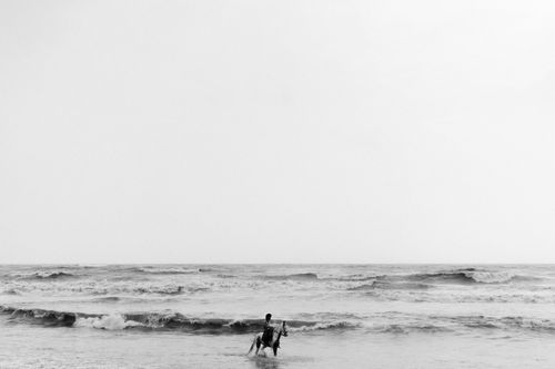 Free A lone horse rider faces the ocean waves in a serene monochrome setting, evoking a sense of calm. Stock Photo