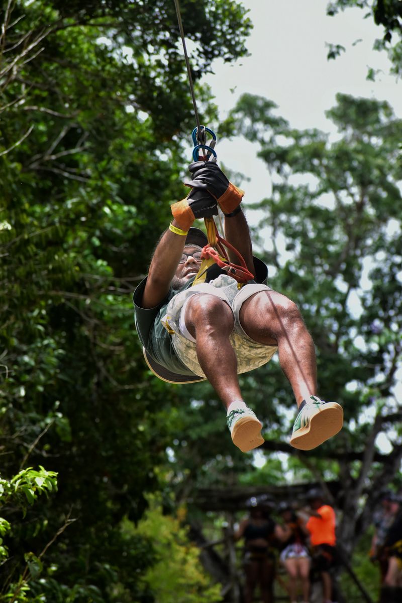Person ziplining through a lush tropical forest on Maui