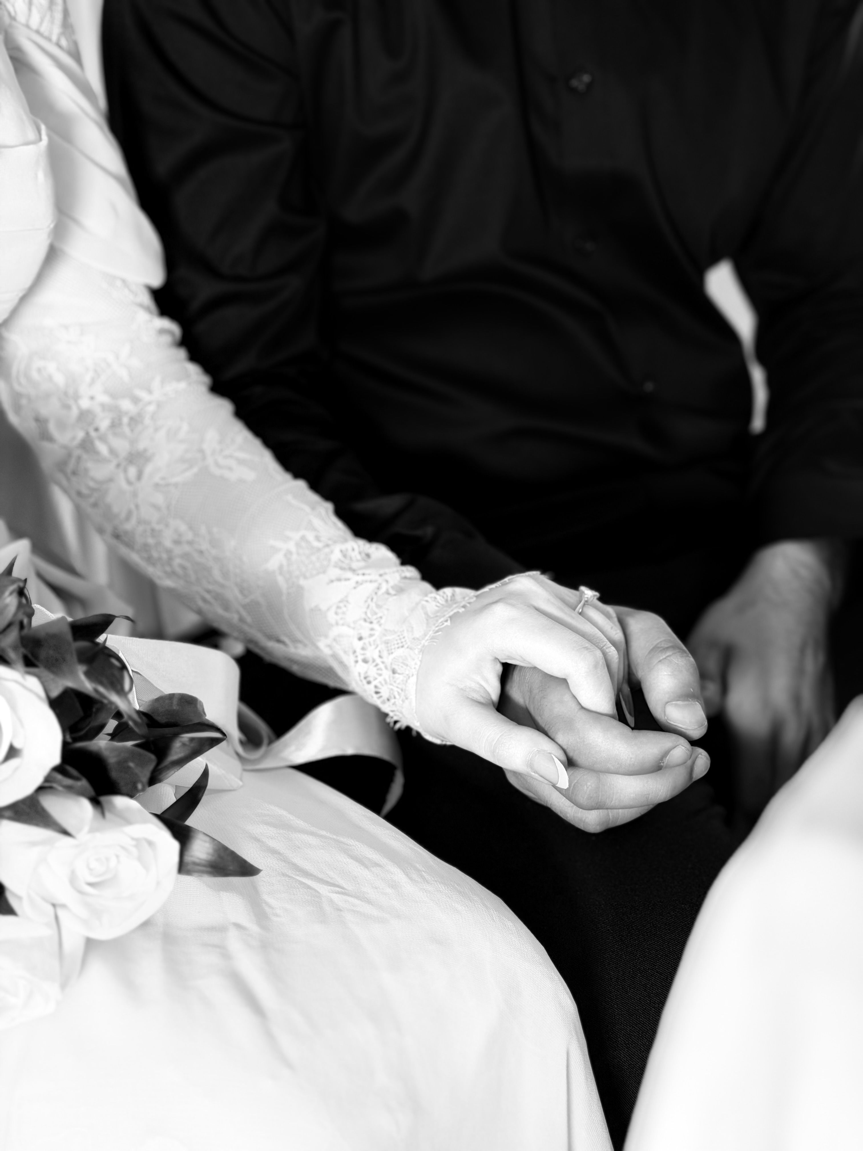 Fotomural Primer plano de una pareja tomada de la mano, capturando un momento íntimo e intemporal de una boda en blanco y negro.