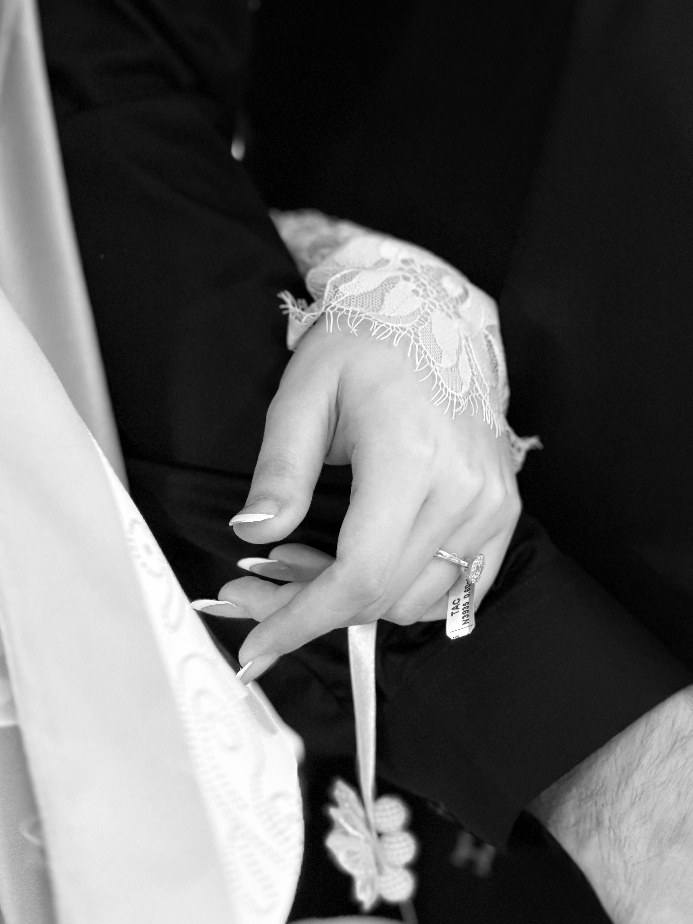 Close-up of couple holding hands in wedding attire, showcasing unity and elegance.