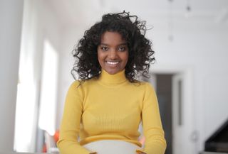A presenter smiling toward the camera in a bright room — photo by Andrea Piacquadio on Pexels