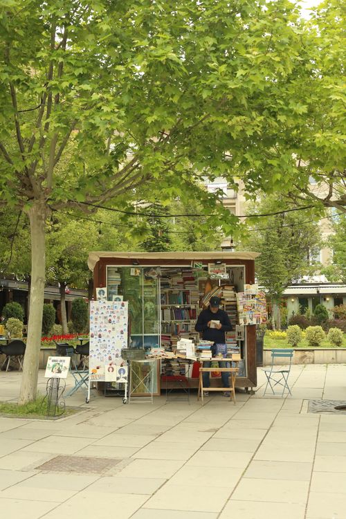 Free A quaint outdoor bookstall under lush green trees in a serene park setting. Stock Photo