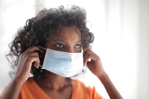 Woman in Orange Crew Neck Shirt Wearing White Face Mask