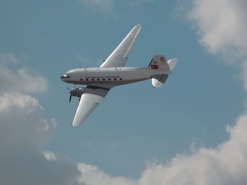 Free A vintage DC-3 plane flying through a bright blue sky, showcasing Turkish Airlines' historical aviation. Stock Photo