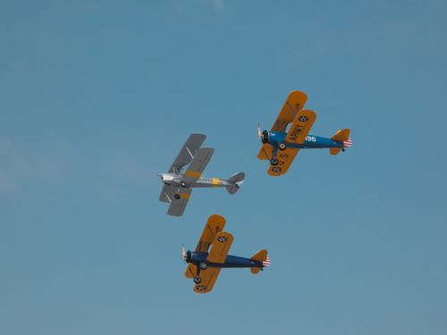 Free Three colorful vintage biplanes performing an aerial display under a clear blue sky, showcasing classic aviation history. Stock Photo