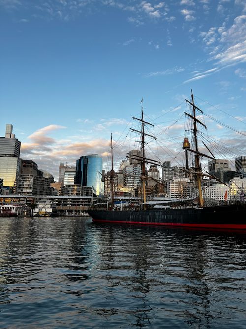 Free A beautiful tall ship docked with the Sydney city skyline in the background at sunset. Stock Photo