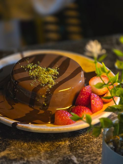 Free Delicious chocolate cake topped with pistachios and fresh strawberries served on a plate. Stock Photo