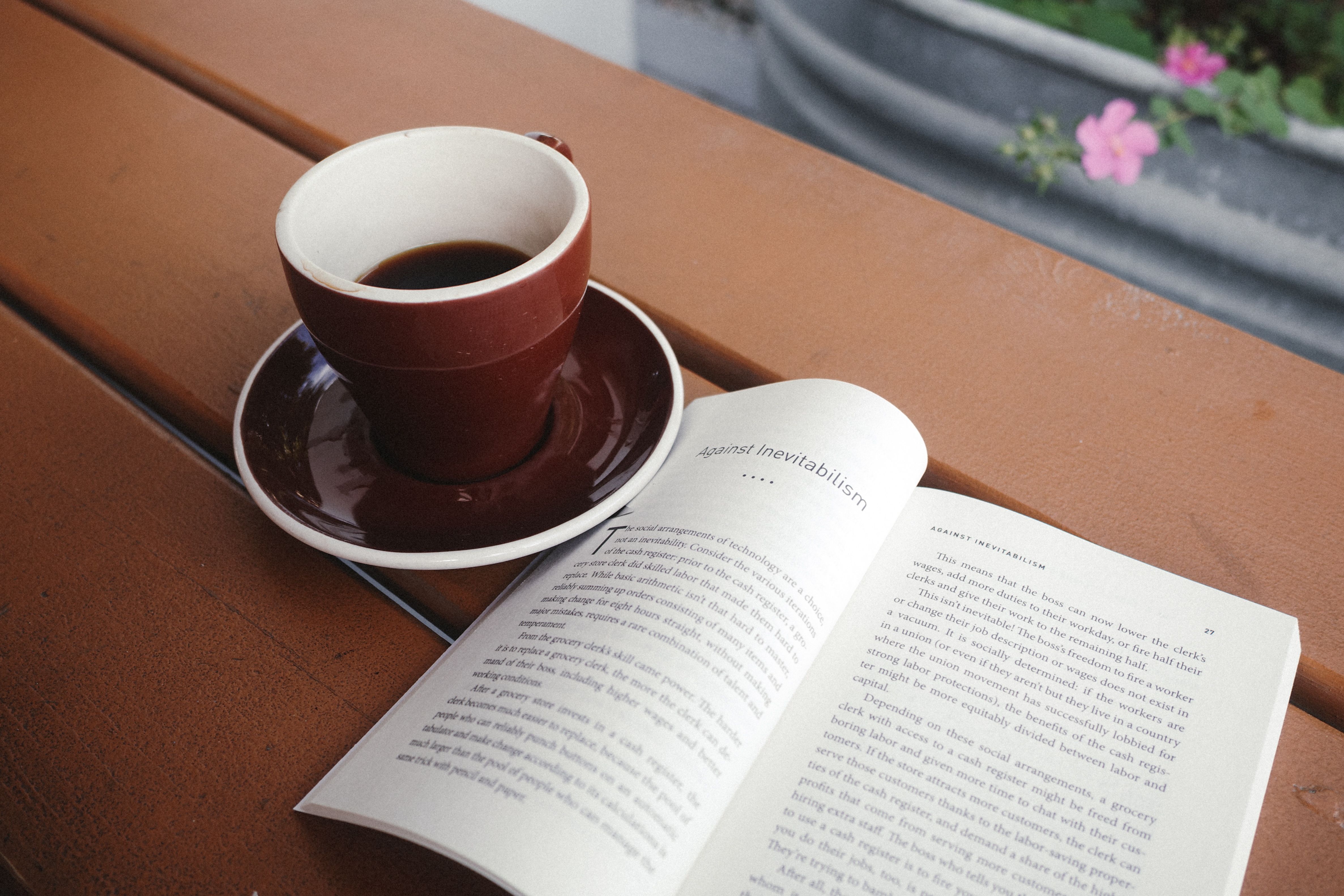 A warm cup of coffee beside an open book on a wooden table, perfect for a relaxing morning.