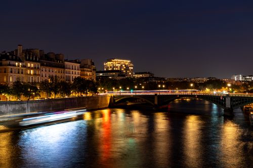 Free Stunning nighttime shot of a Parisian bridge over the Seine River with vibrant city lights reflected in the water. Stock Photo