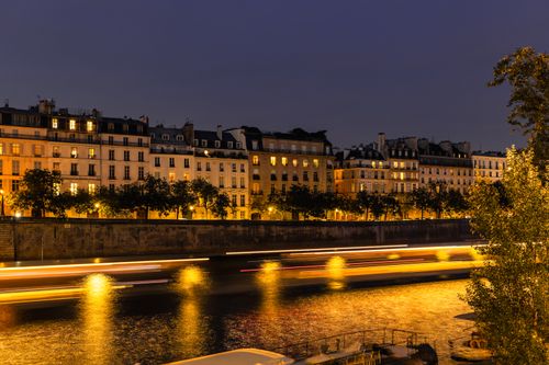 Free Long exposure night shot of Paris buildings and Seine River, capturing light trails and reflections. Stock Photo