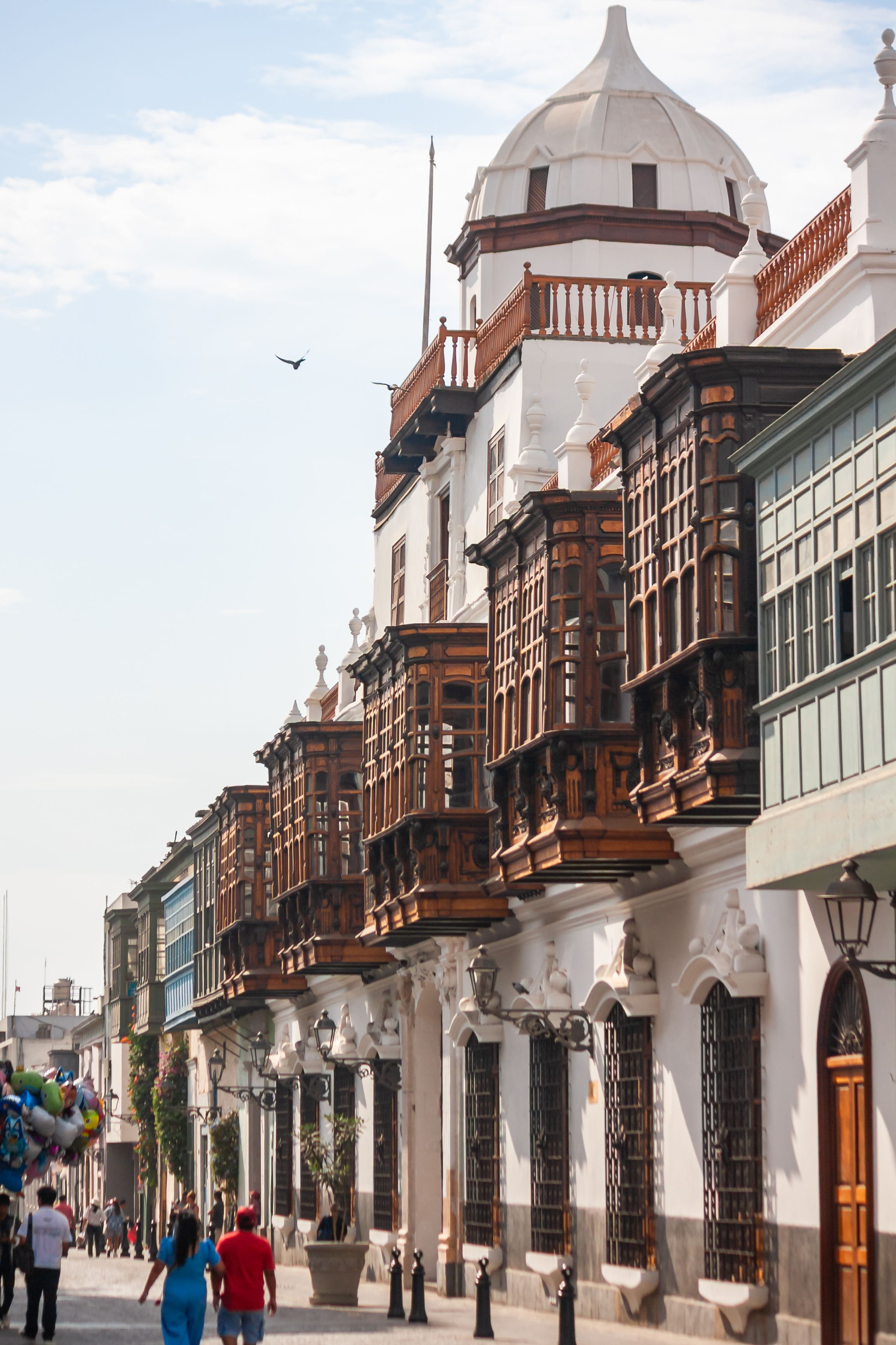 Historic wooden balconies line a street in Lima, showcasing colonial architecture.