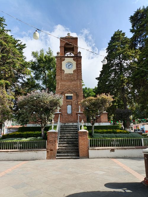Free A picturesque clock tower surrounded by lush trees in a park setting in México. Stock Photo