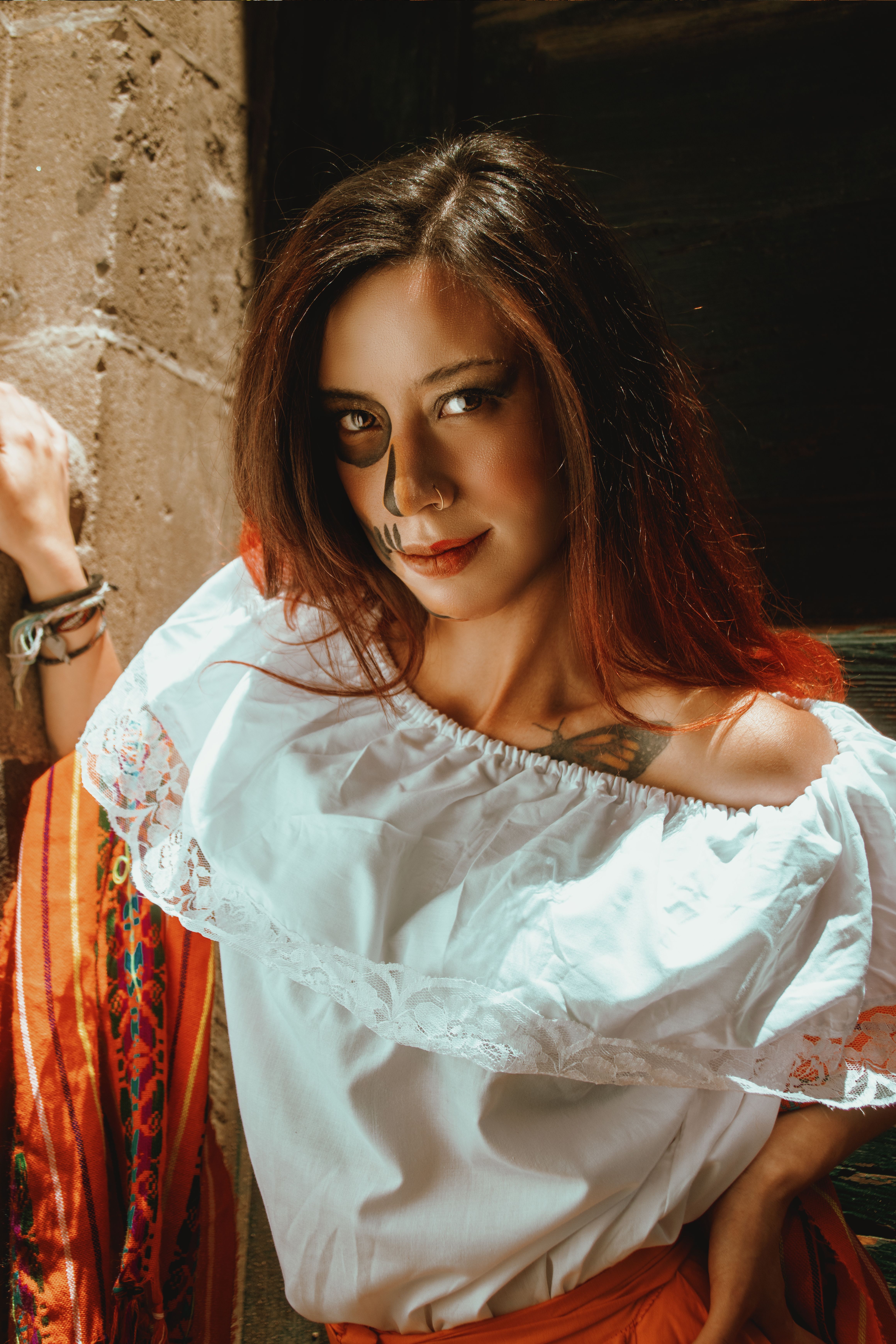 A woman poses with traditional makeup and attire for Day of the Dead, highlighting cultural heritage.