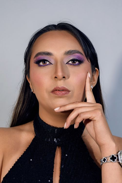 Free Close-up portrait of a woman with bold purple eye makeup wearing a black halter top. Stock Photo