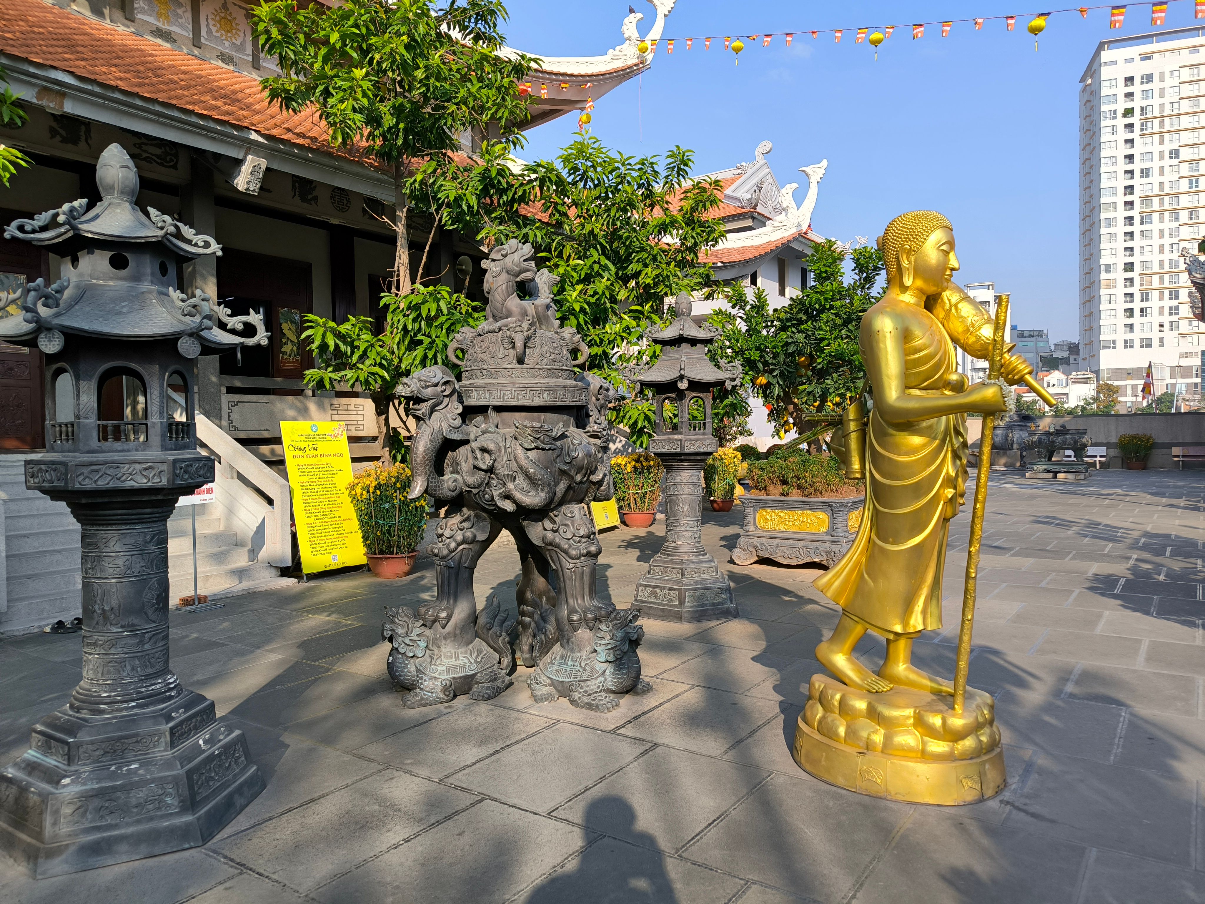 Golden Buddha statue and ornate sculptures at a temple in Ho Chi Minh City, Vietnam, under a sunny blue sky.