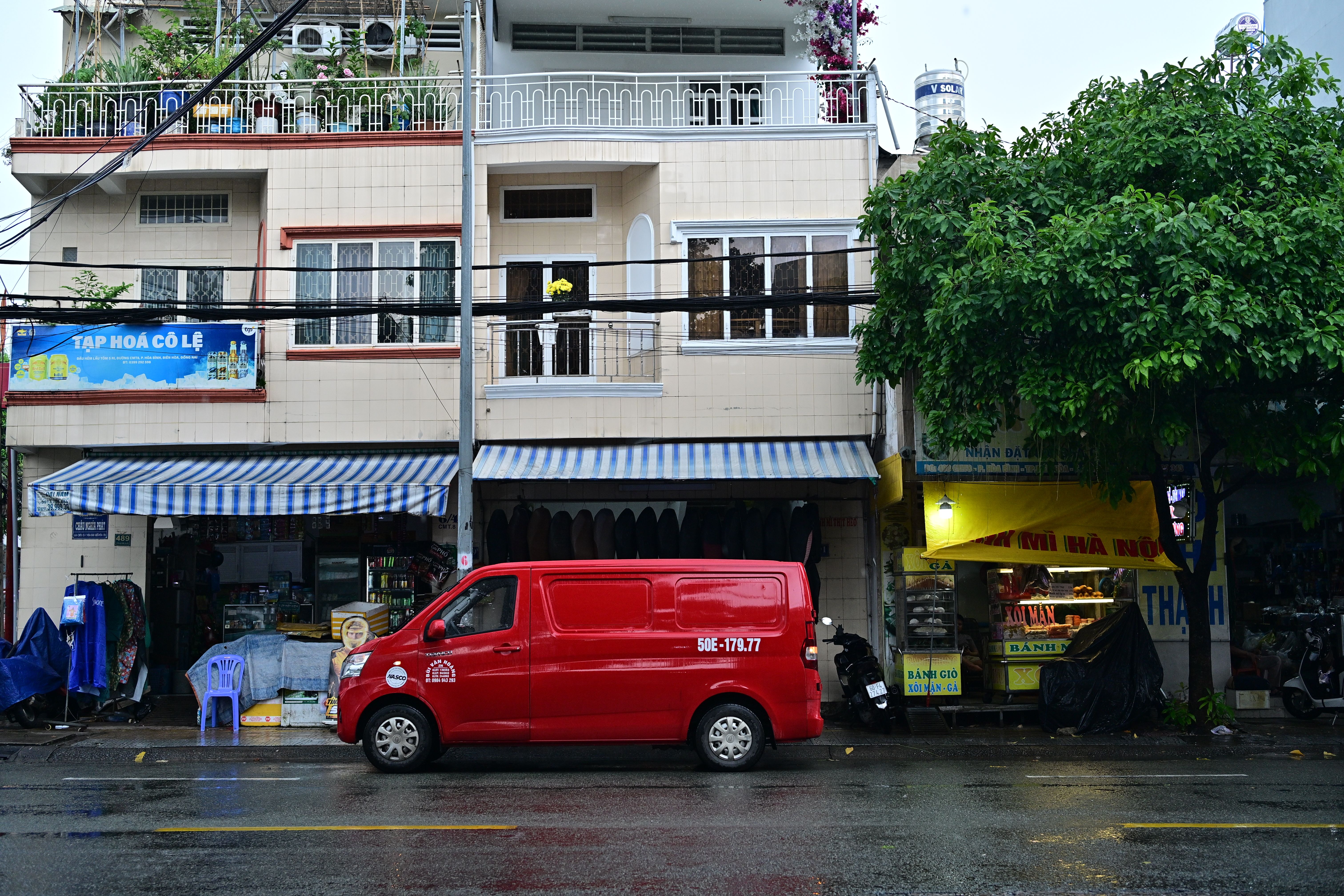 Red van parked outside urban storefronts on a rainy day.