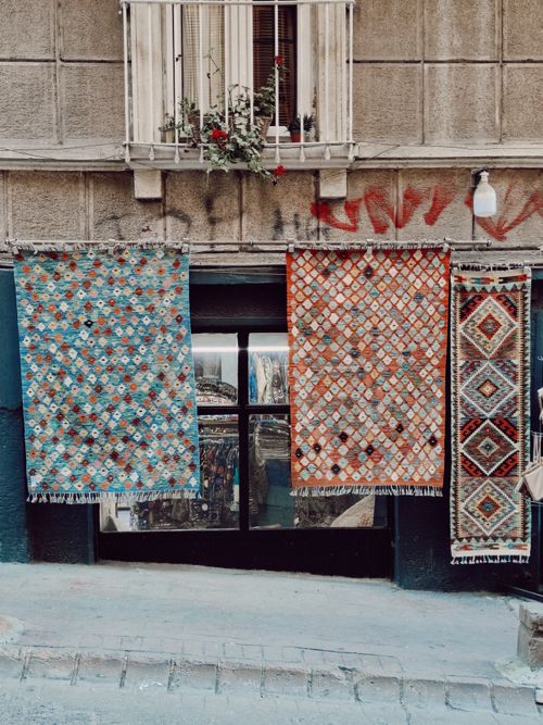Free Vibrant traditional rugs hanging outdoors against a rustic urban wall. Stock Photo