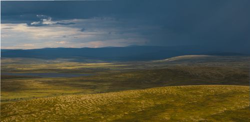 Free A vast landscape of rolling hills under a dramatic stormy sky, capturing nature's beauty. Stock Photo