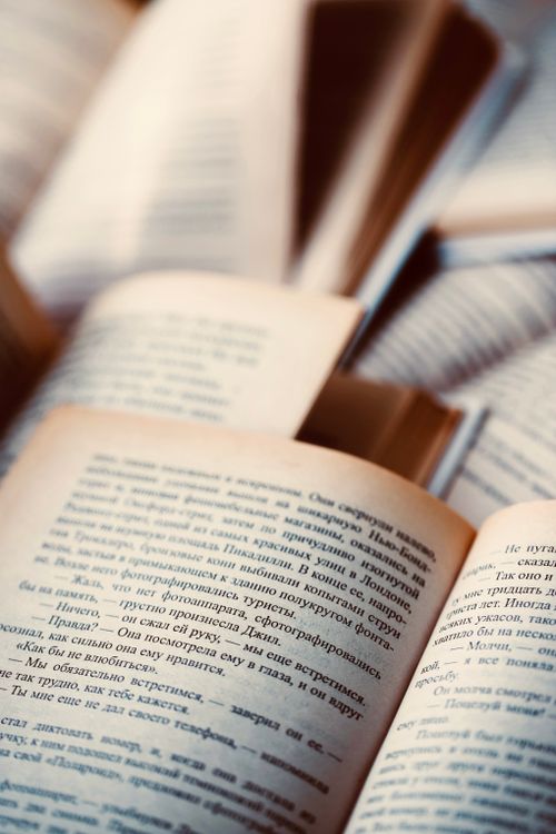 Free An artistic close-up of open books with readable text in warm lighting, ideal for literary themes. Stock Photo