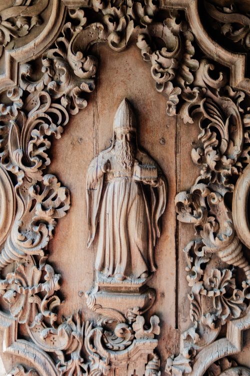 Free Detailed wood carving featuring a religious figure surrounded by ornate patterns. Stock Photo
