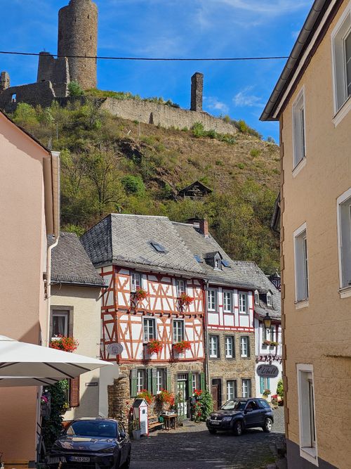 Free A picturesque view of a German village with half-timbered houses and historic castle ruins in the background. Stock Photo