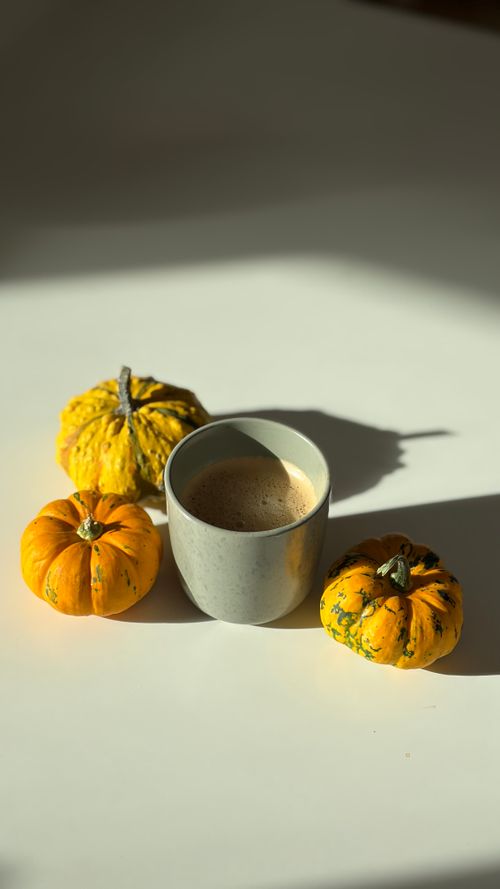 Free Warm coffee surrounded by mini pumpkins, capturing the essence of fall. Stock Photo