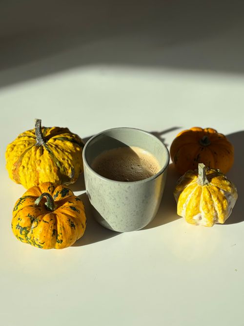 Free A cozy autumn scene with a cup of coffee surrounded by bright decorative pumpkins. Stock Photo