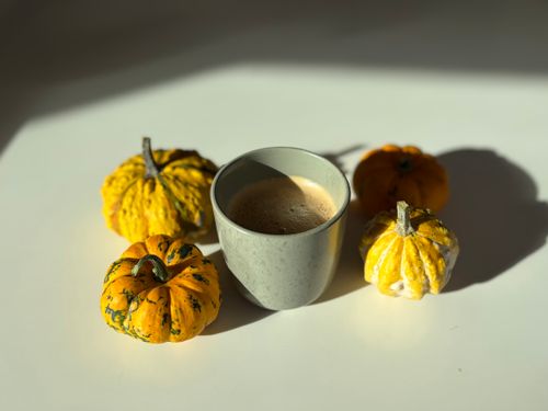Free Cozy autumn setup with a cup of coffee surrounded by decorative gourds. Stock Photo