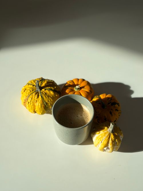 Free Cozy autumn setup with a cup of coffee surrounded by decorative pumpkins. Stock Photo