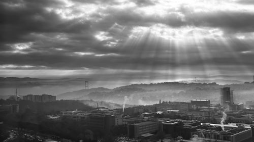 Free Black and white photo of Istanbul skyline with sun rays breaking through clouds above Bosphorus Bridge. Stock Photo