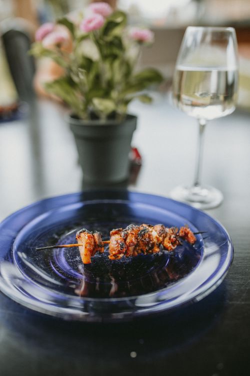 Free Delicious grilled meat skewer served on a blue plate with a wine glass. Stock Photo