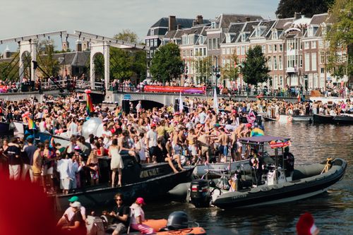 Free Crowded celebration on boats at Amsterdam's picturesque canals. Festive atmosphere with diverse crowd. Stock Photo