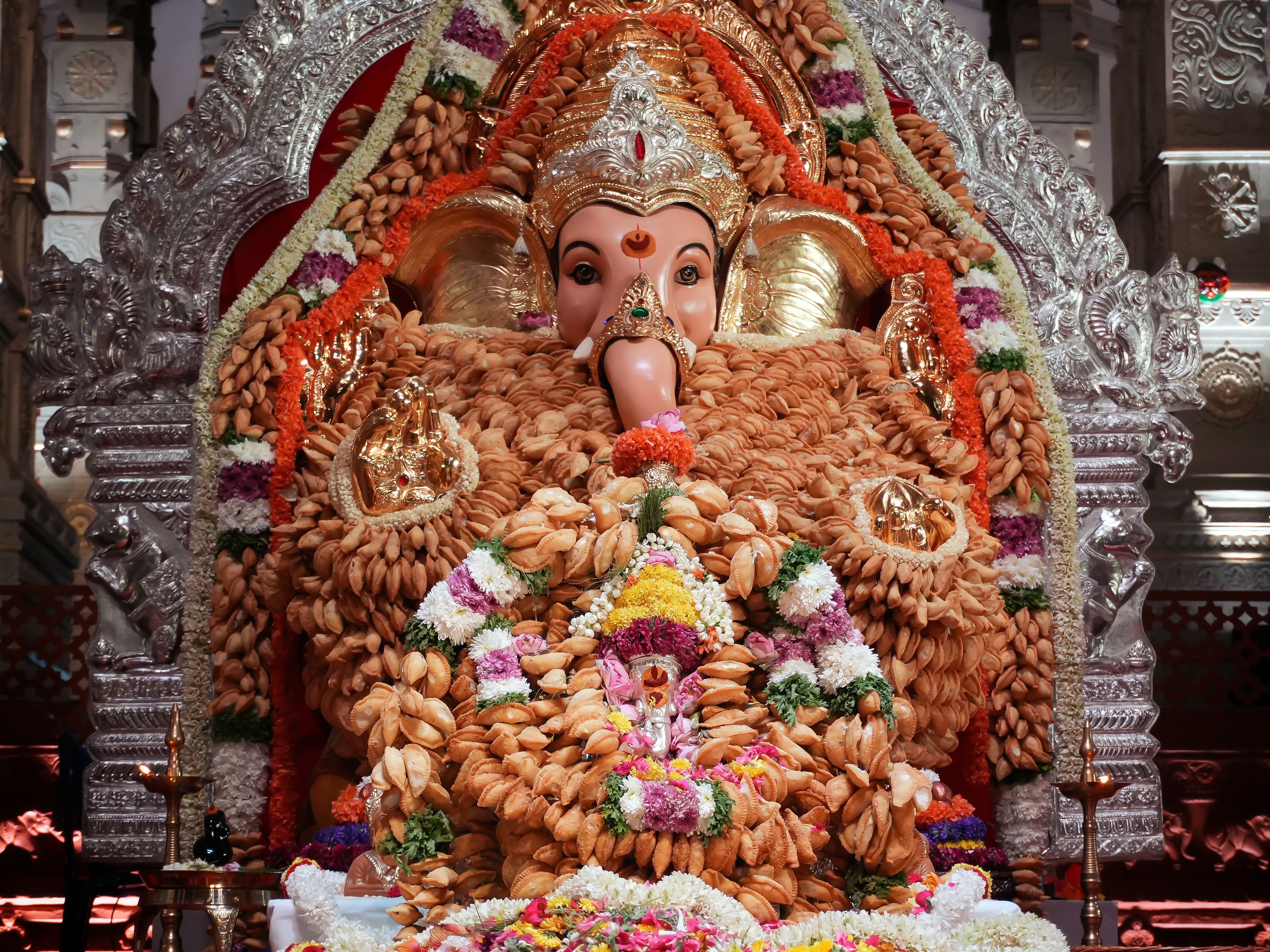 Colorful Ganesh statue with elaborate floral decorations and traditional offerings.