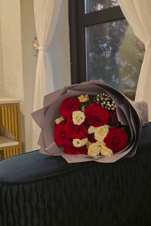 Free A beautifully arranged bouquet of red and white roses placed on a sofa indoors, captured with a soft natural light. Stock Photo