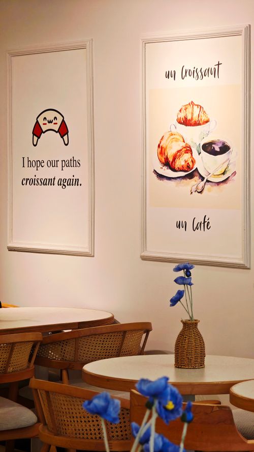 Free Cozy café interior featuring whimsical croissant-themed artwork, perfect for a breakfast setting. Stock Photo