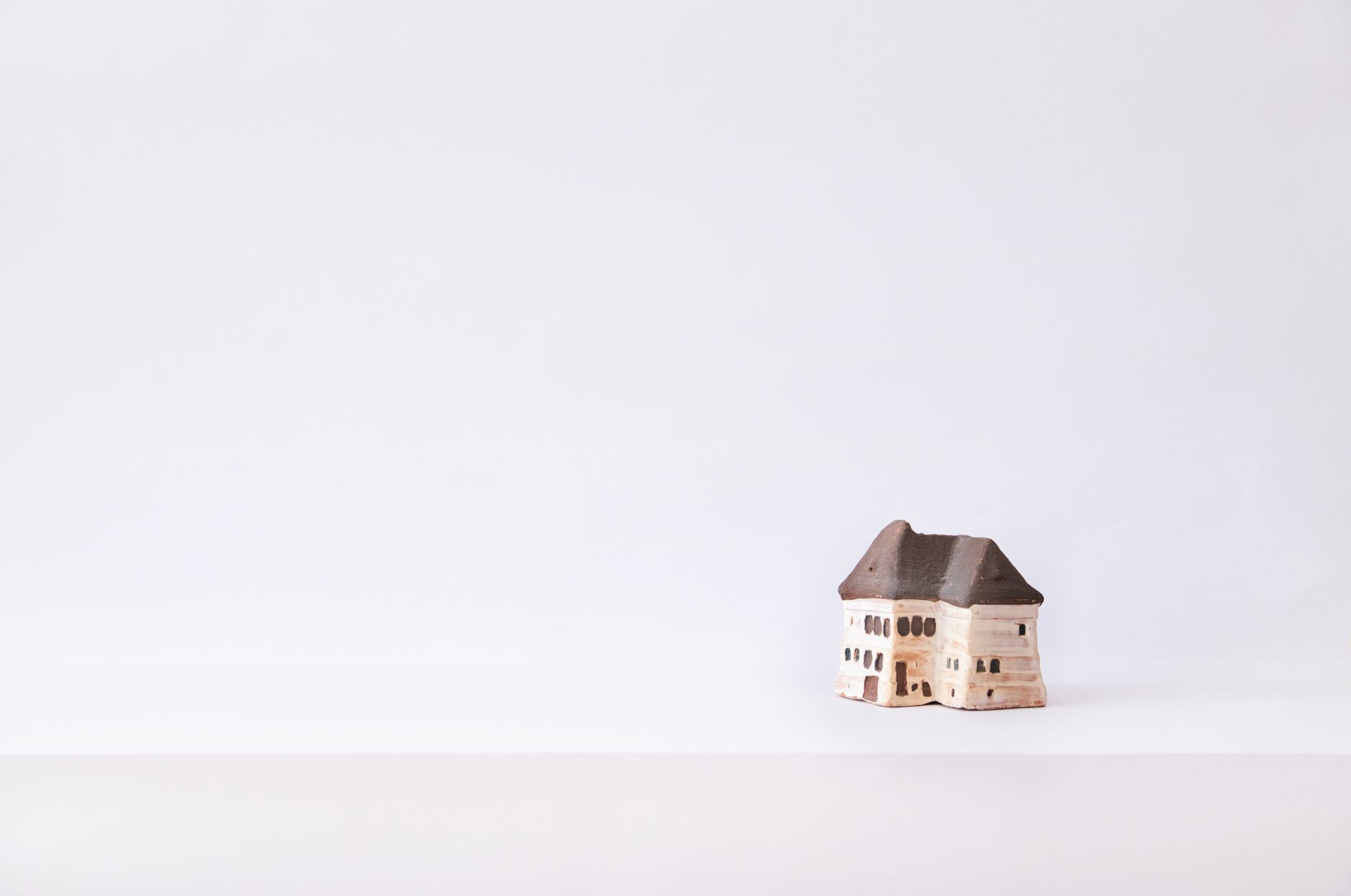 Simple handmade clay house on a plain white background, perfect for creative design projects.
