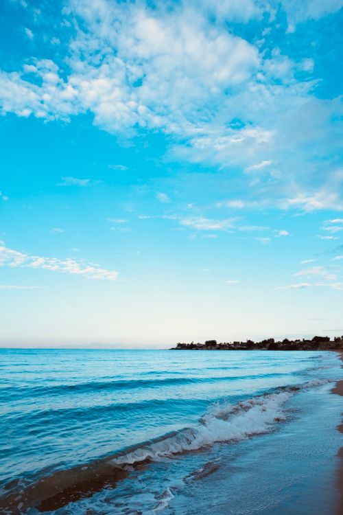 Free Calm early morning beach with gentle waves and a serene sky, perfect for a peaceful escape. Stock Photo