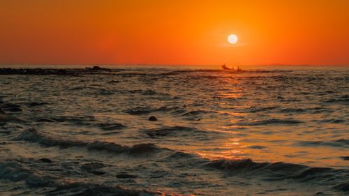 Free Serene sunset over the ocean in Quảng Trị, Vietnam, with a boat silhouetted against the vibrant sky. Stock Photo