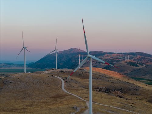 Free Scenic view of wind turbines on a mountain hillside during sunset, promoting renewable energy. Stock Photo