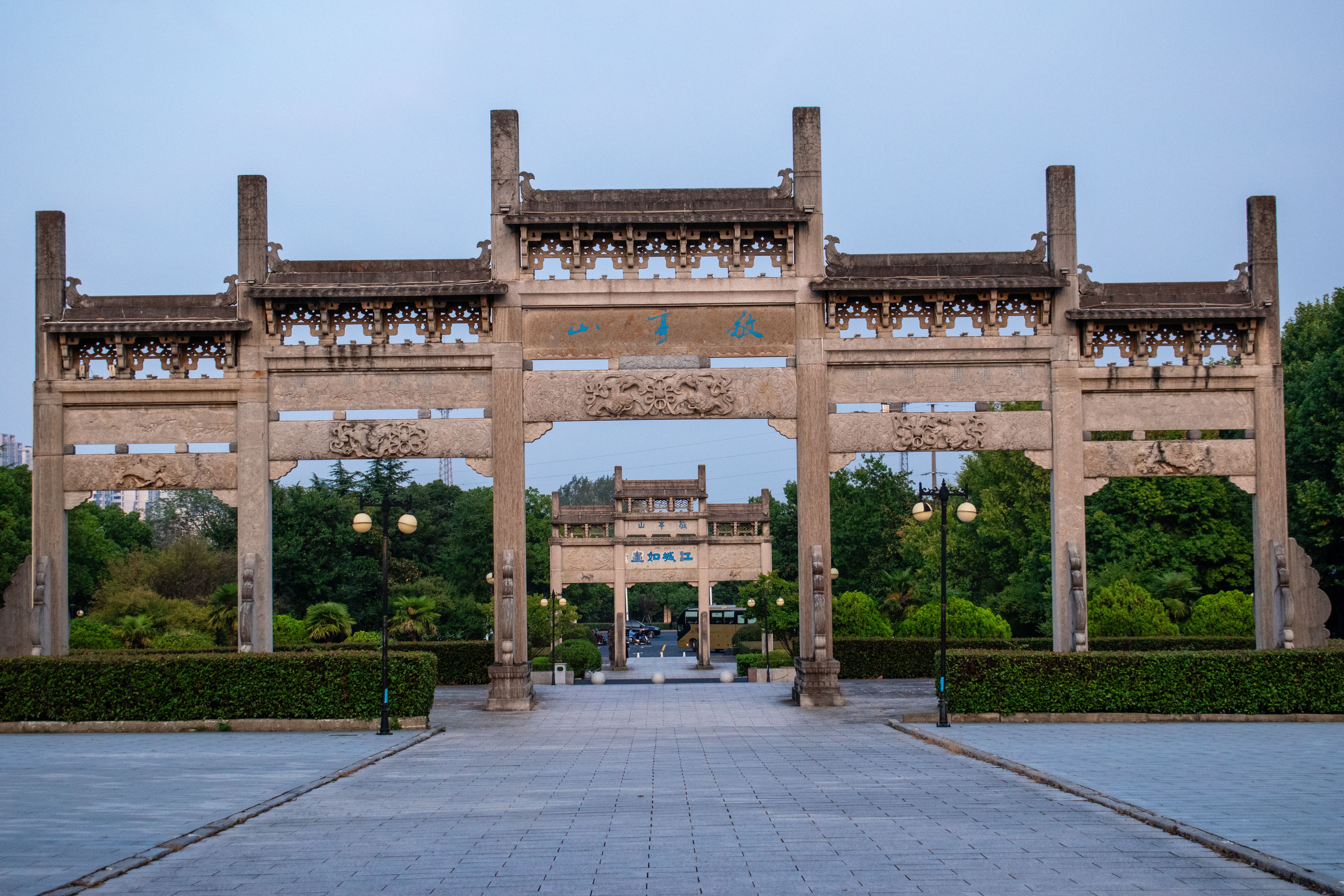 Serene view of a traditional Chinese archway in a lush, quiet park setting.